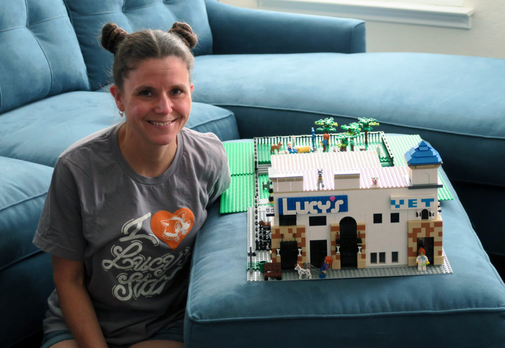 Woman sitting next to Lucy's Doggy Daycare and Spa Lego sculpture